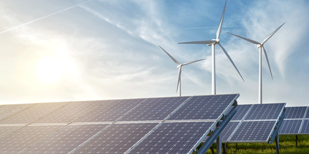 Solceller och vindkraftverk med bakgrund av blå himmel och lysande sol.